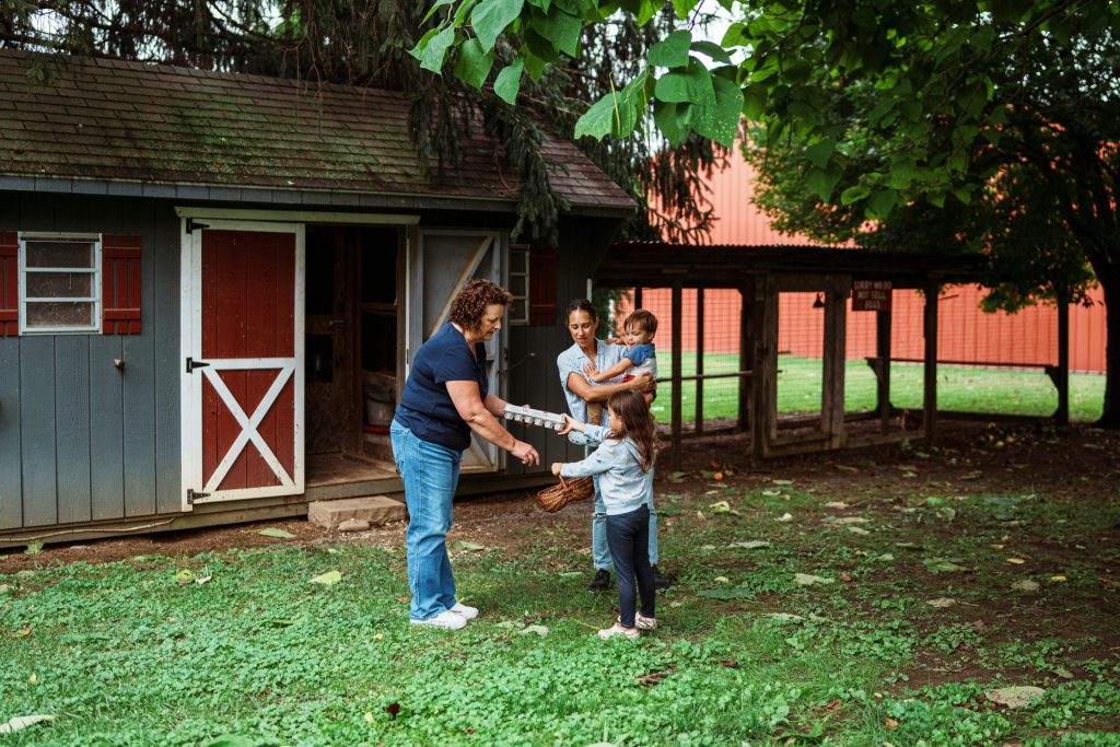 Family interacts with a woman near a shed.